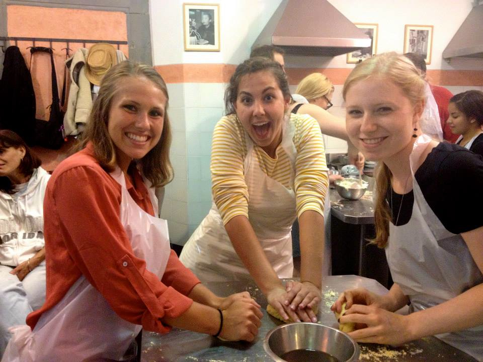 three students knead dough in a kitchen in Florence, Italy